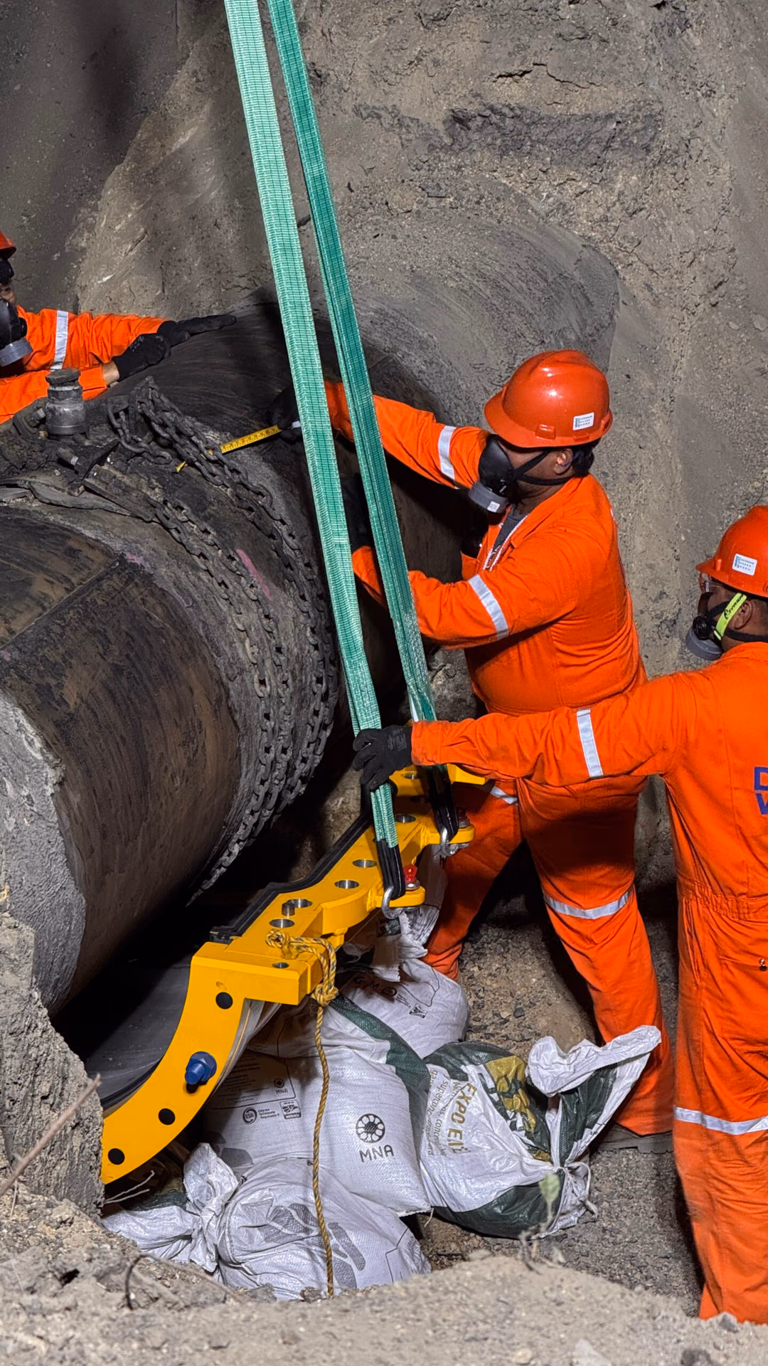 Crew installing a bolted sleeve on a buried pipeline